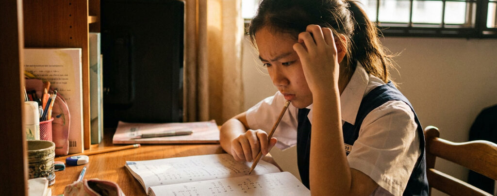 Primary 5 girl looking confused at maths problem at home in Singapore